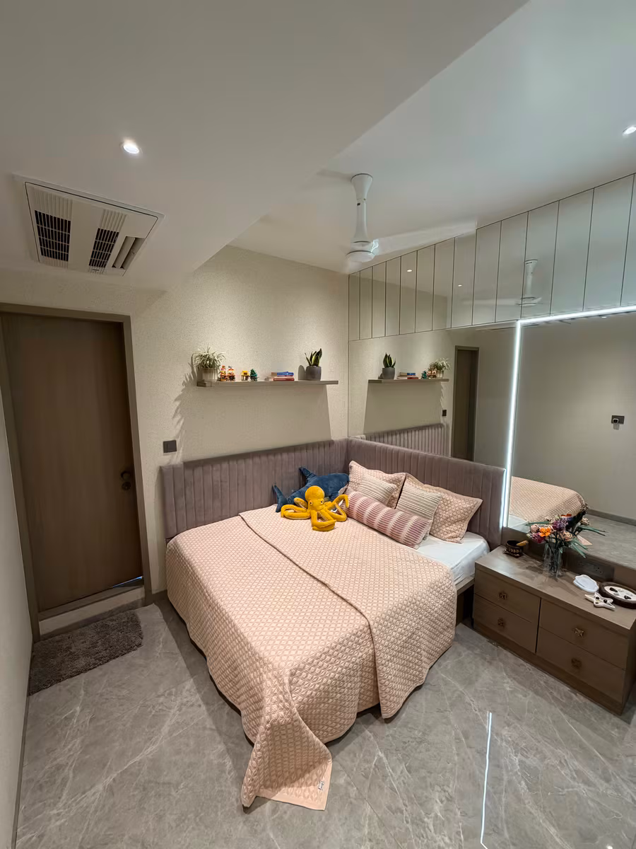 Bedroom with a full-height mirrored sliding wardrobe and bedside storage by ASK Design and Build
