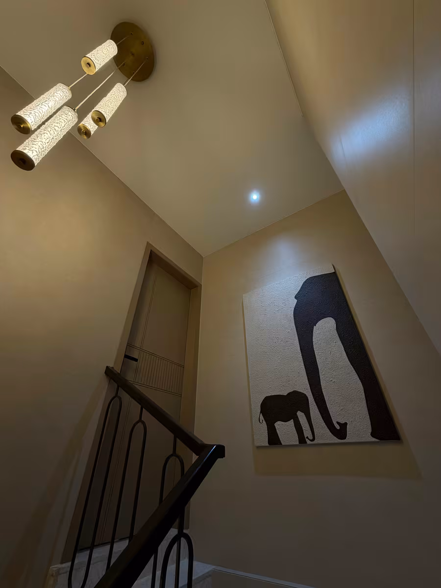 Stairwell with textured wall art and a cluster of pendant lights by ASK Design and Build