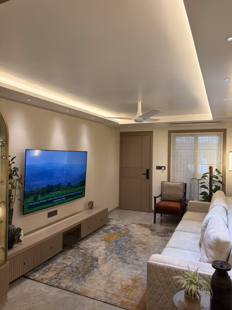 Living room with layered cove lighting and a wall-mounted entertainment unit by ASK Design and Build