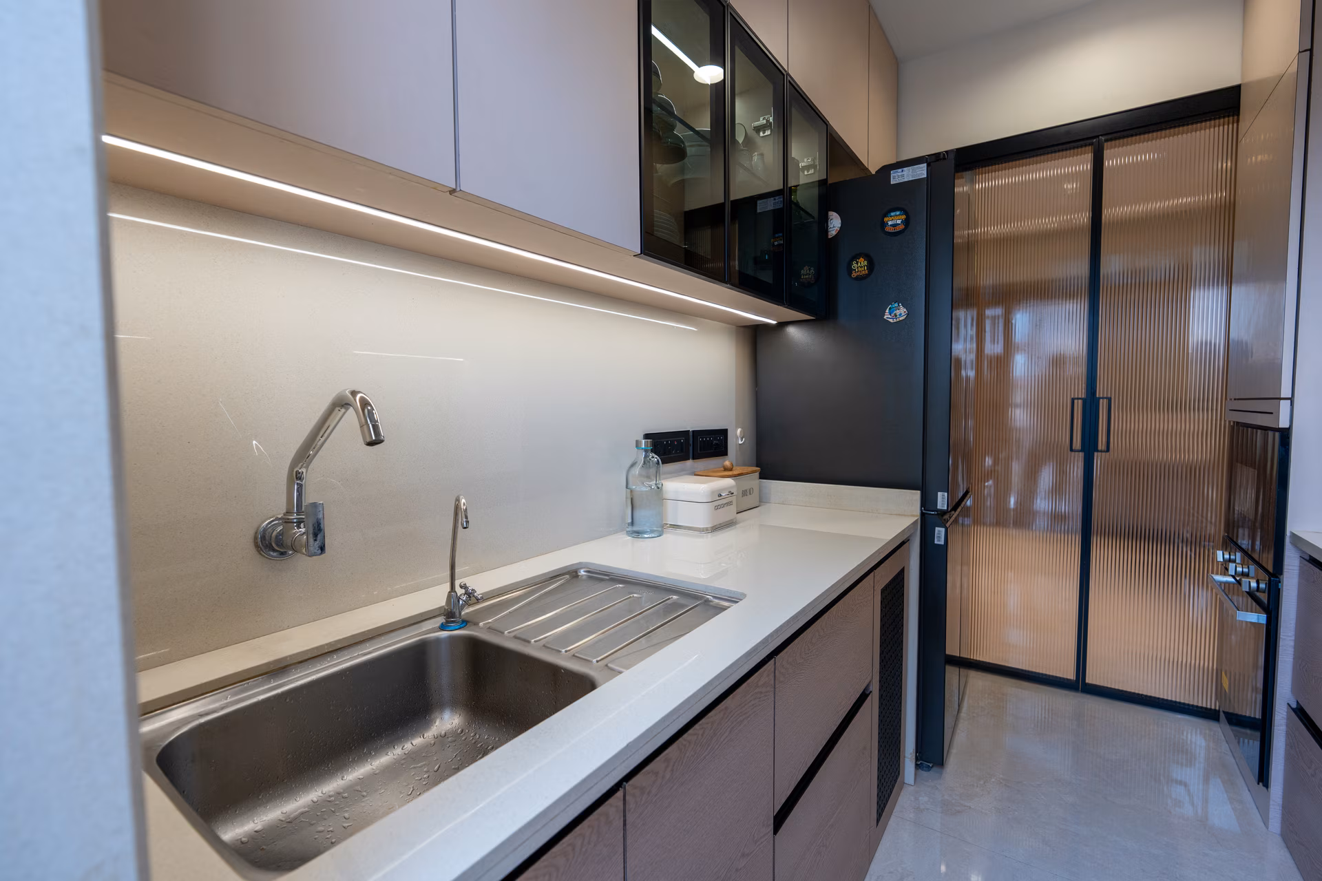 Compact modular kitchen with under-cabinet lighting and smart storage by ASK Design and Build