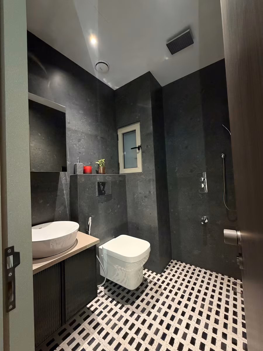 Bathroom finished in dark stone-look tiles with a patterned floor and a compact vanity by ASK Design and Build