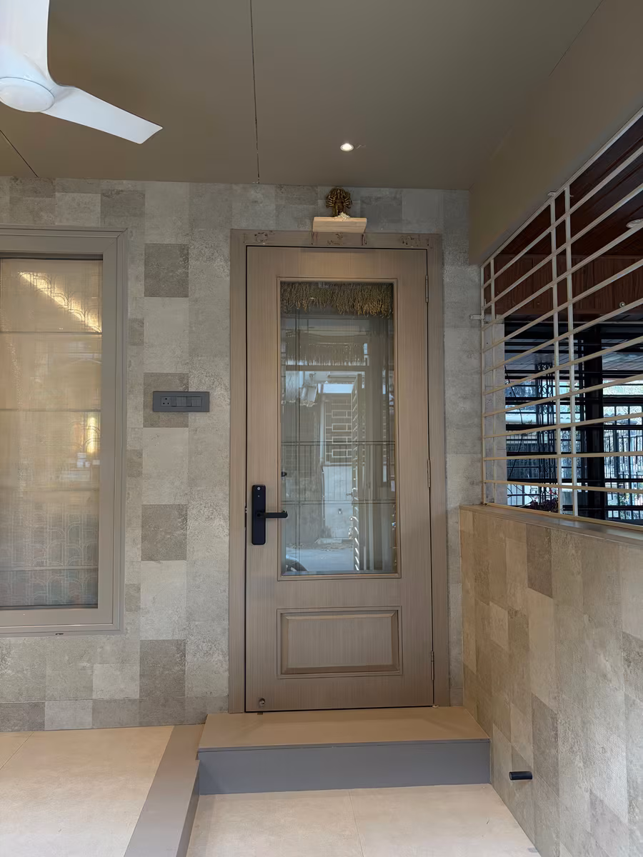 Entrance foyer with stone-look wall tiles and a glazed timber door by ASK Design and Build