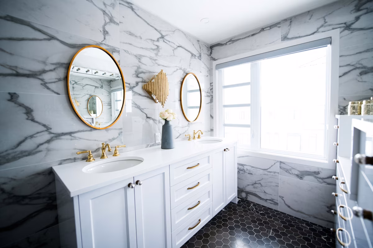 Luxury marble bathroom with gold accents, featuring dual circular mirrors and white vanity