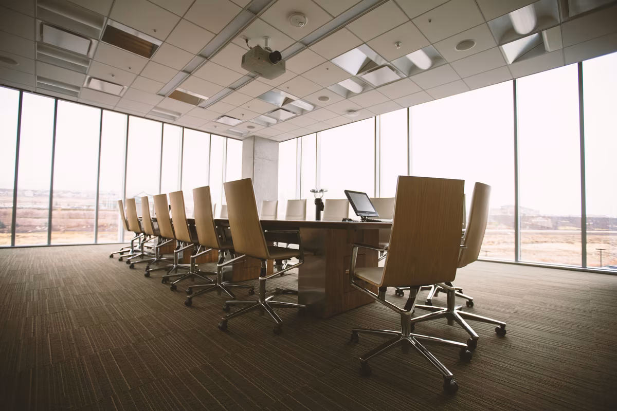 Modern conference room with a large wooden table, ergonomic chairs, and floor-to-ceiling windows