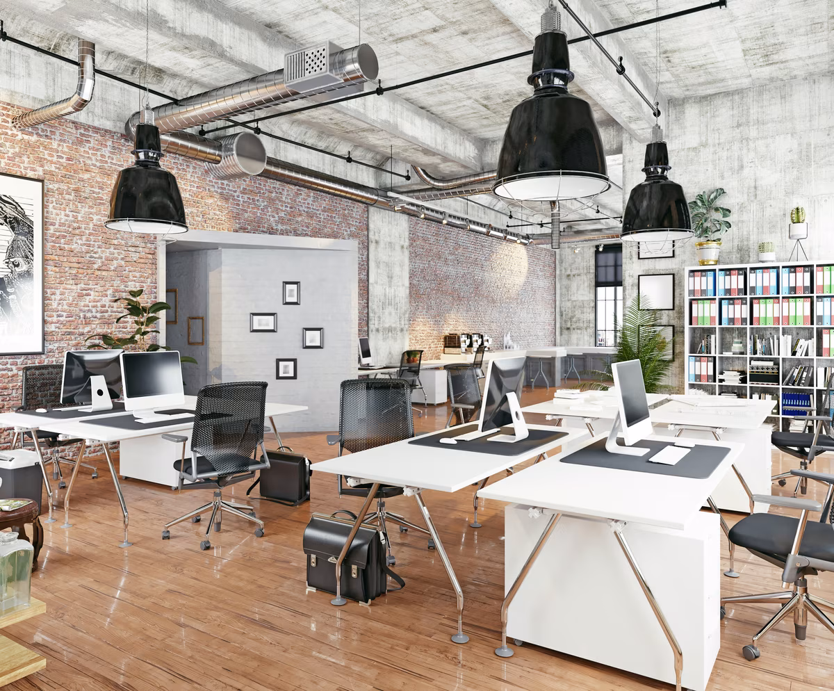Industrial open office with exposed brick walls, modern workstations, and large pendant lights