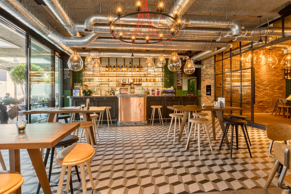 Industrial chic café with exposed ductwork, wooden tables, and eclectic decor