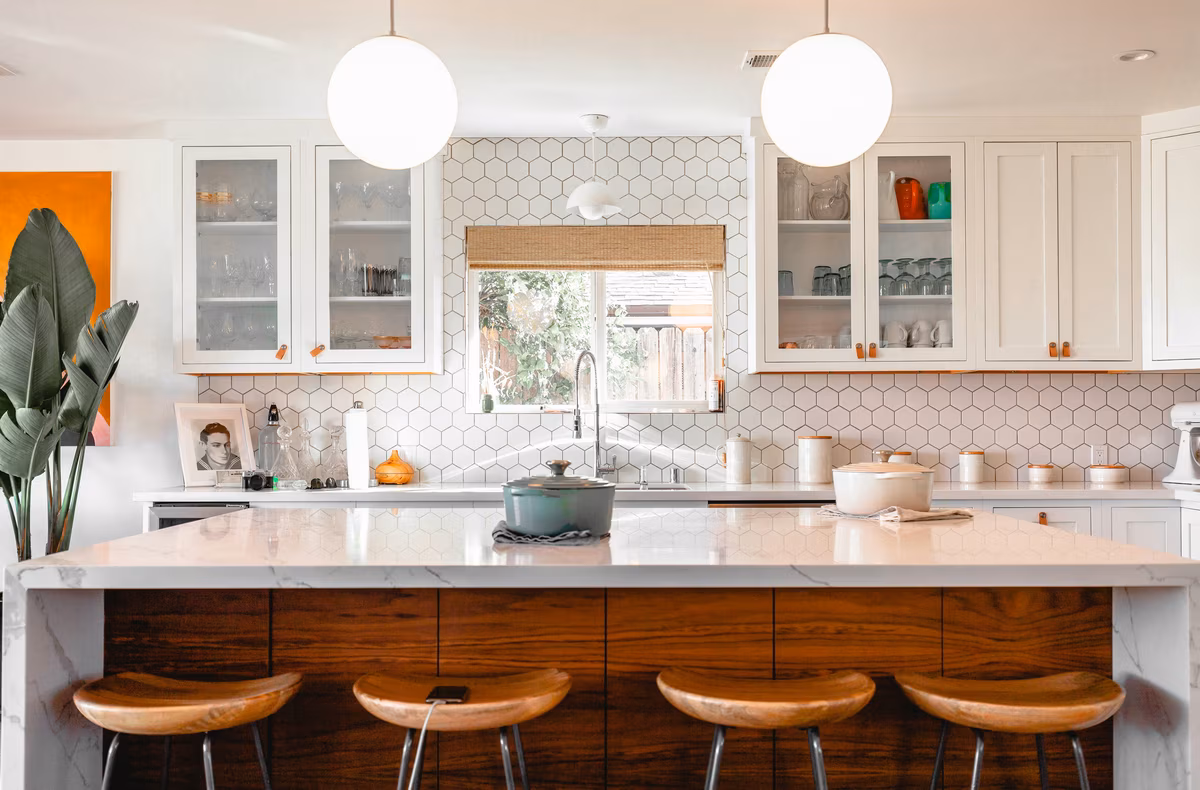 Modern white kitchen with hexagonal backsplash and globe pendant lights