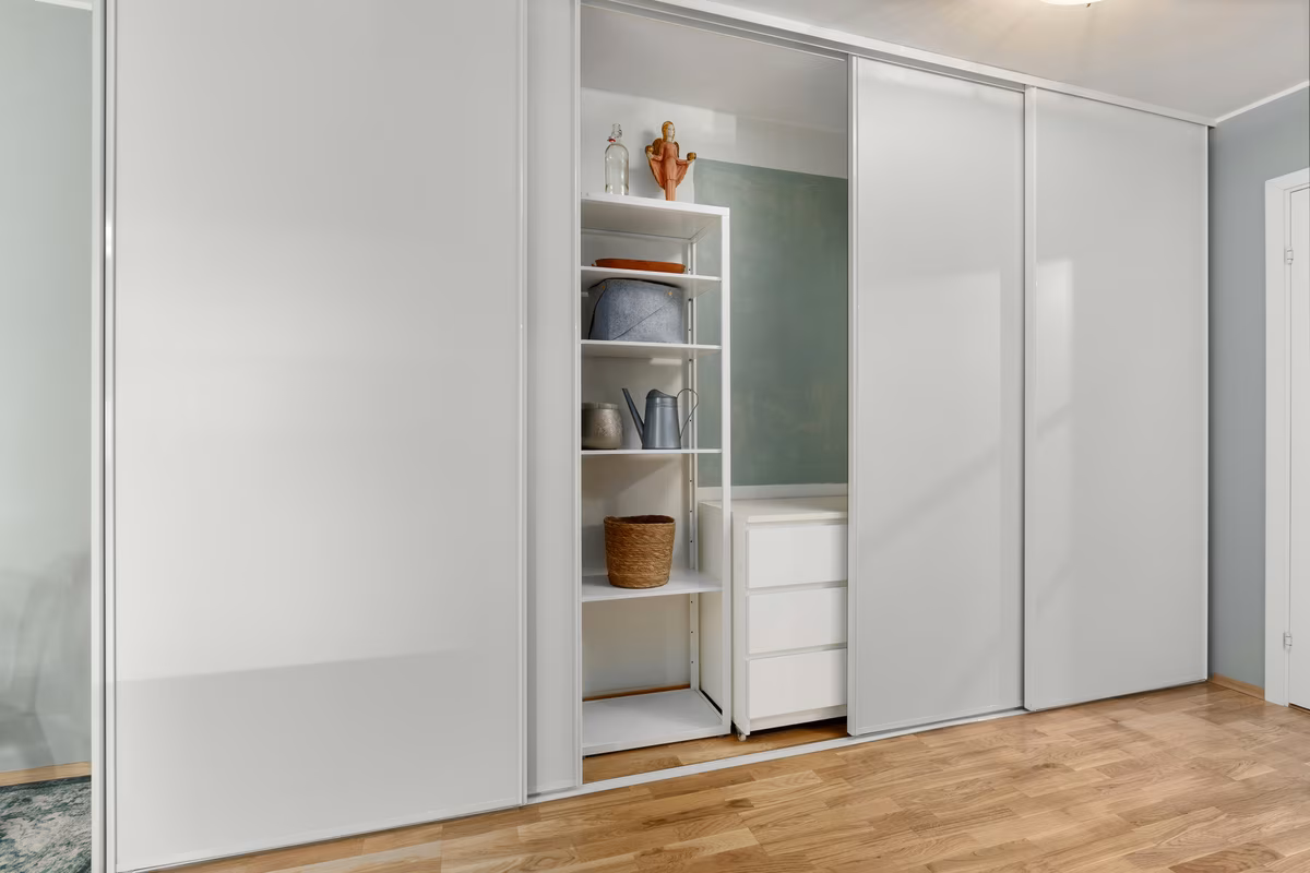 Full-wall white wardrobe with sliding panels and integrated open shelving