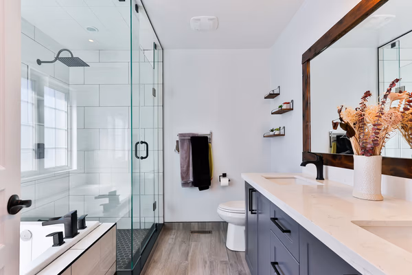 Modern transitional bathroom featuring black fixtures, white subway tiles, and navy blue vanity with natural accents