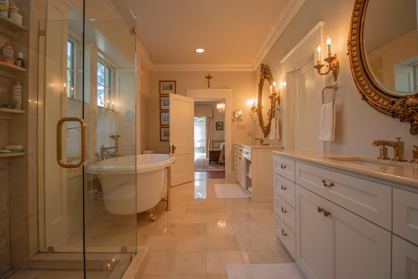 Traditional luxury bathroom with gold fixtures, ornate mirrors, and classic white cabinetry