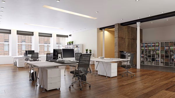 Modern open office with white desks, ergonomic chairs, and large windows