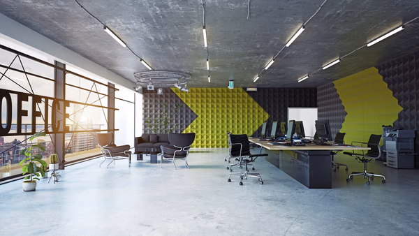 Modern industrial workspace with collaborative desks, vibrant accents, and acoustic panels