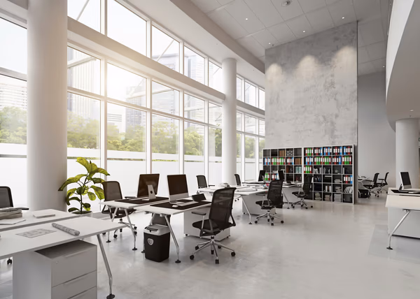 Spacious modern office with white desks, ergonomic chairs, and large windows