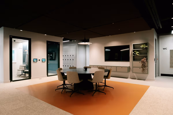 Modern collaborative meeting space with round table, swivel chairs, and wall-mounted display