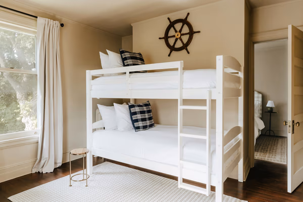Modern nautical kids room with white bunk bed and ship wheel decor