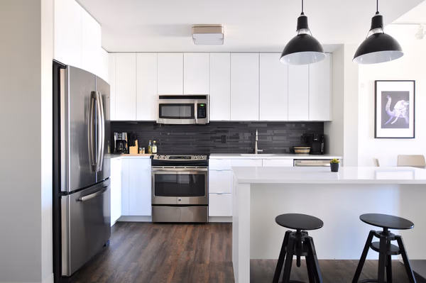 Modern white kitchen with black slate backsplash and industrial pendant lighting