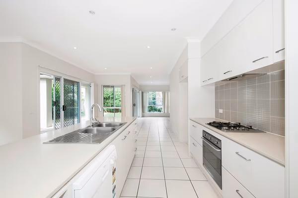 Bright white galley kitchen with multiple windows and garden views