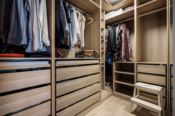 L-shaped walk-in closet with light oak finish and extensive drawer storage