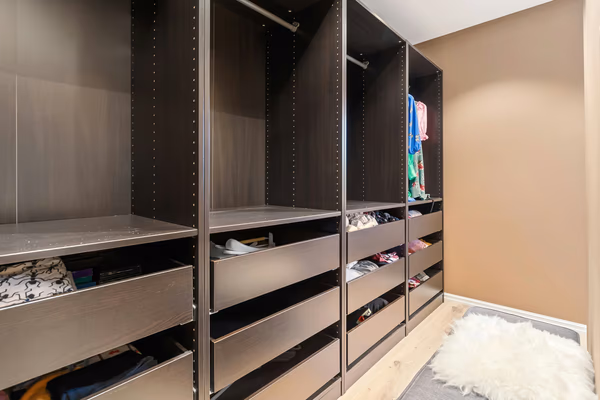 Modern walk-in closet with dark finish and extensive drawer system
